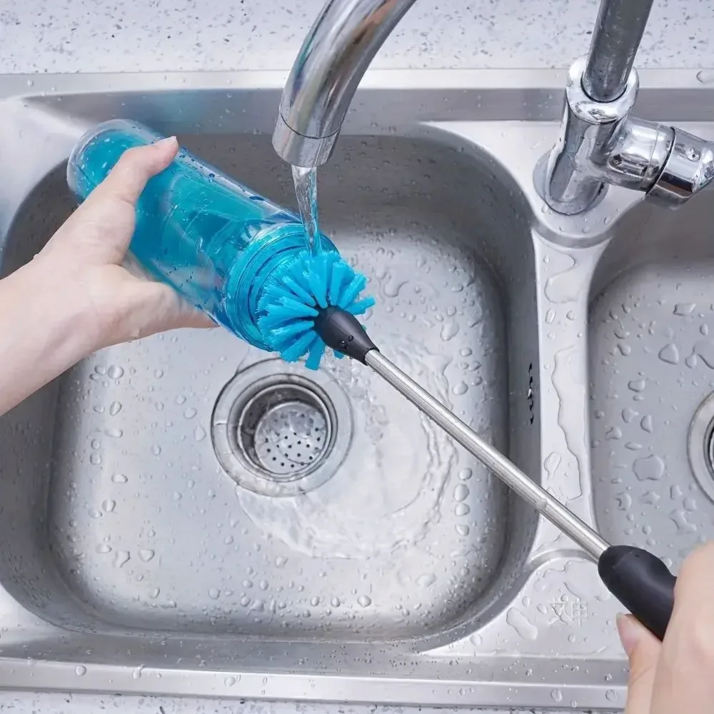 Long handled blue bottle brush cleaning the inside of a reusable bottle under running water